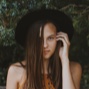 women with hat standing in front of leaves